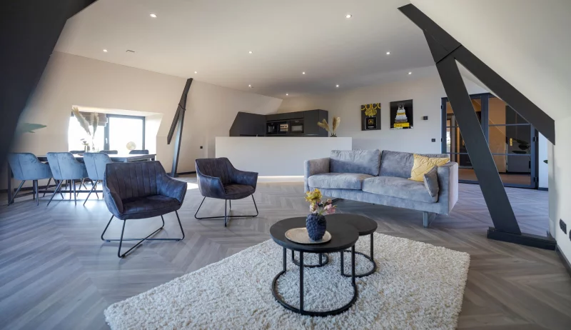 Living room with wooden floor, featuring a cozy couch and chairs.