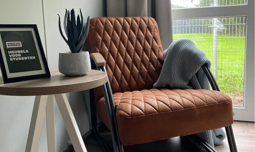 A chair and table in a room with a picture and plant on the table