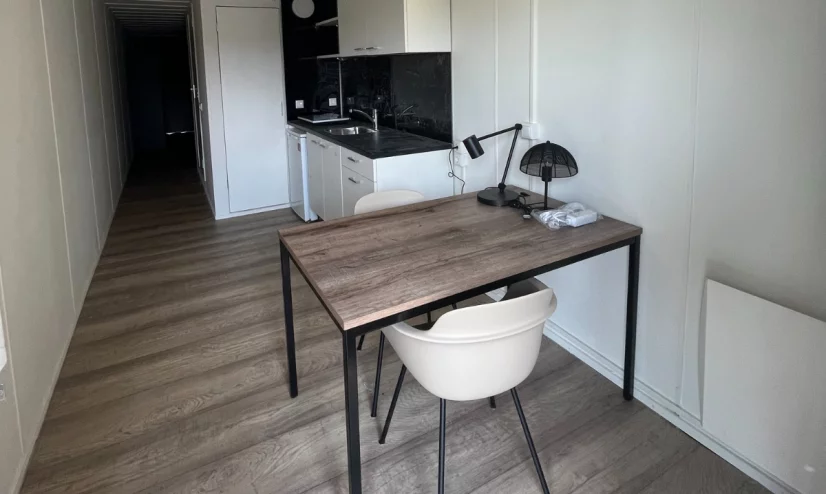 A container home for students with a table, chairs and kitchen