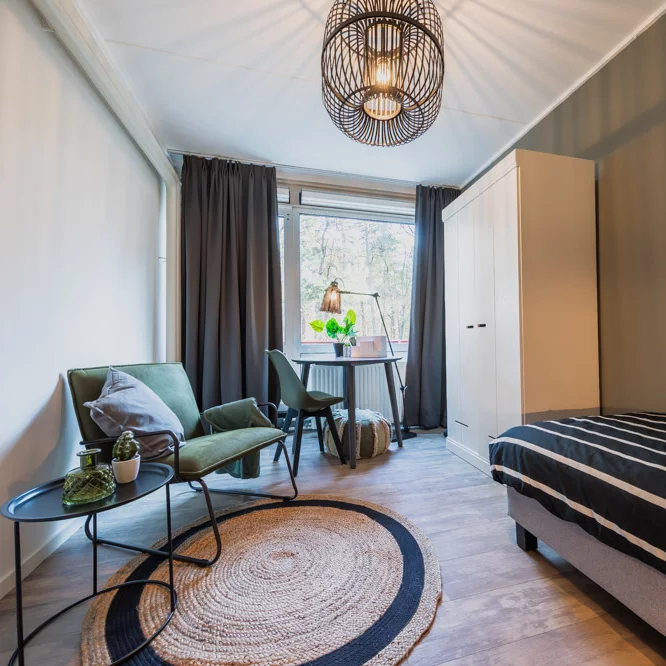  Furnished student bedroom featuring a bed, chair, and table