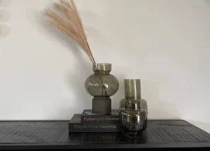 Decorative black vase with feather on top of two books